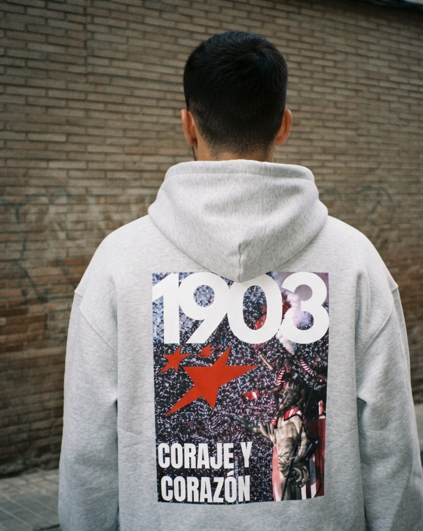 Sudadera con capucha Coraje y Corazón gris puesta, aficionado
